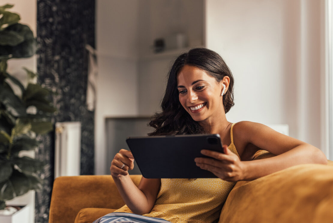 woman with ipad and airpods on sofa